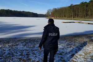 Policjant stojący na brzegu zamarzniętego jeziora