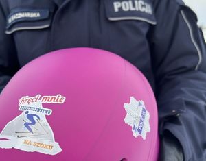 Policjant  trzymający różowy balon z napisem kręci mnie bezpieczeństwo na stoku.