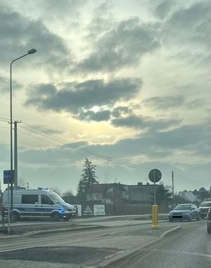 Policyjny radiowóz stojący na poboczu przy niebieskim audi stojącym na drodze.