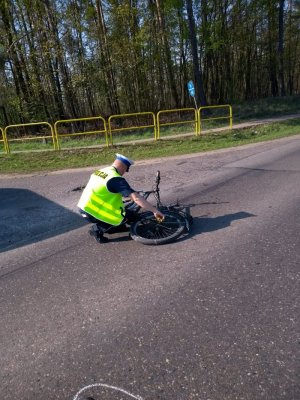 Policjant ruchu drogowego podczas oględzin roweru, który uczestniczył w zdarzeniu drogowym