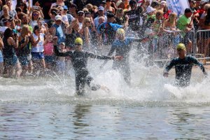 Uczestnicy triathlonu wbiegaja do wody