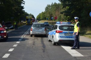 Policjant, radiowóz i auto uczestniczace w zdarzeniu