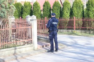 Policjant stoi pod domem osoby objetej kwarantanną