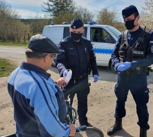 Policjanci rozmawiaja z meżczyzna i wręczają maseczkę