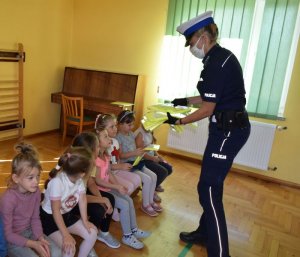 Policjantka rozdaje kamizelki odblaskowe