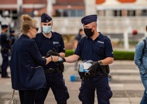 Policjanci rozmawiają z kobietą i daja jej maseczkę