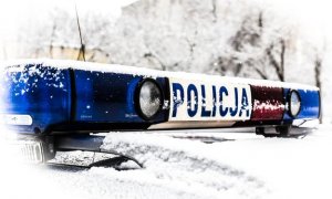 Na tle zimowej aury oświetlenie na dachu radiowozu z napisem Policja