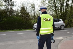 Policjant stoi przy drodze z miernikiem prędkości