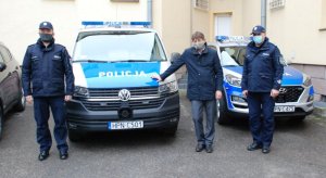 Dwóch policjantów oraz mężczyzna stoją w obrębie nowego radiowozu