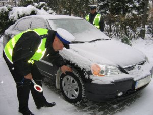 Policjant sprawdza stan bieżnika w samochodzie