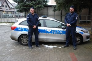 Policjanci stoja przed radiowozem