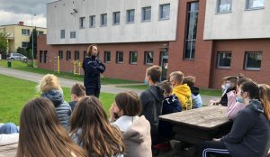 Policjantka stoi przed grupą młodzieży na zajęciach na powietrzu