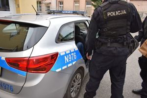 Policjant stoi przy drzwiach radiowozu