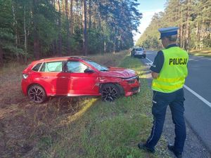 policjanta na tle rozbitego czerwonego samochodu