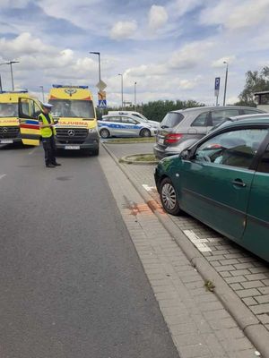 policjant stoi na tle 2 karetek pogotowia i radiowozu