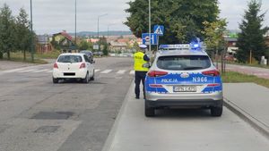 policjant mierzący prędkość przy oznakowanym radiowozie w rejonie przejścia dla pieszych