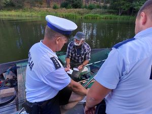 dwoje policjantów na łódce kontrolujących rybaka