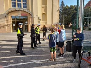 3 UMUNDUROWANYCH POLICJANTÓW WRĘCZA DZIECIOM OPASKI ODBLASKOWE