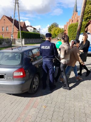 Na zdjęciu policjant dokonujący kontroli drogowej, stoi przy samochodzie