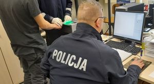 umundurowany policjant siedzący na krześle przed monitorem komputera