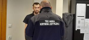 policjant w czarnym polarze z napisem technika kryminalistyczna stojący plecami