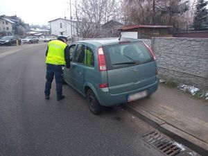 NA ZDJĘCIU WIDOCZNY SAMOCHÓD OSOBOWY I STOJĄCY PRZY NIM POLICJANT