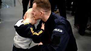 klęczący policjant przytulający dziecko