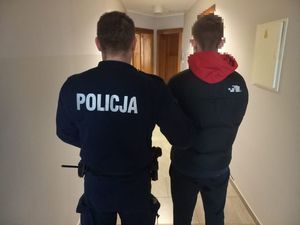 umundurowany policjant prowadzący zatrzymanego