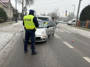 policjant w kamizelce odblaskowej stojący na jedni  przy rozbitym