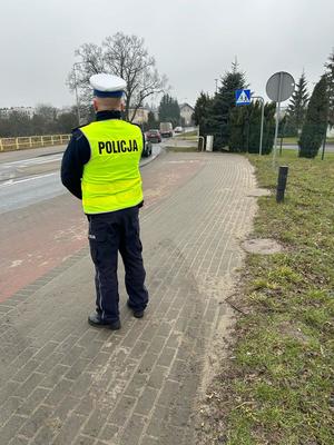 policjant w żółtej kamizelce stojący przy przejściu dla pieszych