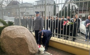 Policjanci składający kwiaty przed upamiętniającym obeliskiem