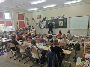 policjant w szkolnej klasie stojący na tle tablicy wokół siedzą dzieci