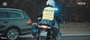 policjant  w żółtej kamizelce odblaskowej na policyjnym motocyklu