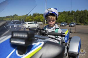 chłopczyk siedzący na policyjnym motocyklu w czapce policjanta ruchu drogowego