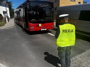 Policjant na jezdni stojący przed autobusem