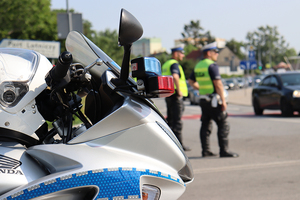 policyjny motocykl. w tle soją dwaj umundurowani policjanci