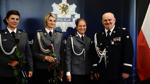 Czterech policjantów w wyjściowych mundurach policji stojących na granatowym tle.