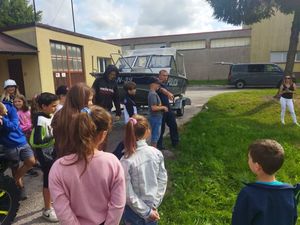 Na zdjęciu widać policjanta z dziećmi, a w tle widoczna jest łódź policyjna.