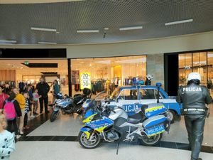 policyjny motocykl stojący wewnątrz budynku, obok stoi umundurowany policjant