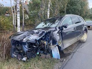 Czarny samochód z rozbitym przodem stojący na poboczu