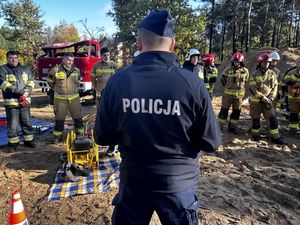 Policjant stojący tyłem rozmawiazjący ze srazakami.