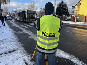 Policyjny technik wykonujący pomiary na miejscu zdarzenia drogowego z autobusem