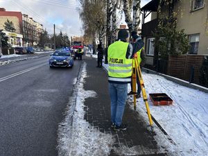 Policyjny technik wykonujący  pomiary na miejscu zdarzenia