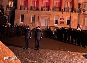 Policjanci stojący na baczność oddający honory