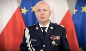 Komendant Główny Policji na tle biało czerewonej flagi