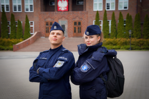 Dwóch umundurowanych policjantów stojących przed szkołą policji w Słupsku