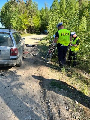 Policjanci na drodze gruntowej wykonujący oględziny rozbitego motoroweru