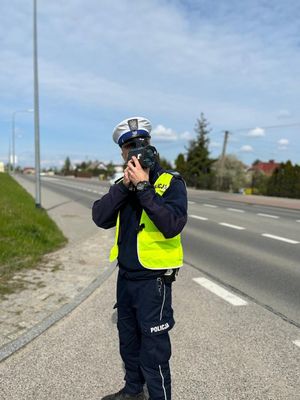 Policjant stojący przy jedni mierzący prędkość