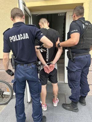 Dwóch policjantów wchodzących do komendy z zatrzymanym