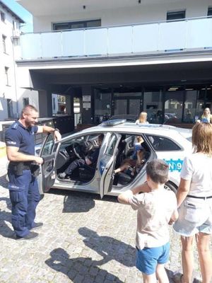 Policjanci przy  radiowozie z przedszkolakami